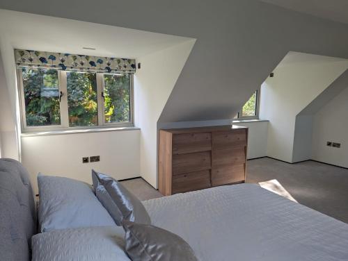 a bedroom with a bed and a dresser and two windows at The Nest at Fairfield in Wargrave