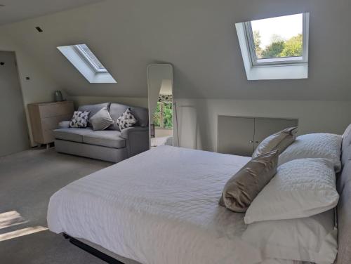 um quarto com uma grande cama branca e um sofá em The Nest at Fairfield em Wargrave