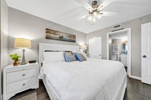 Schlafzimmer mit einem weißen Bett und einem Deckenventilator in der Unterkunft Pelican Beach Resort Unit 1109 in Destin