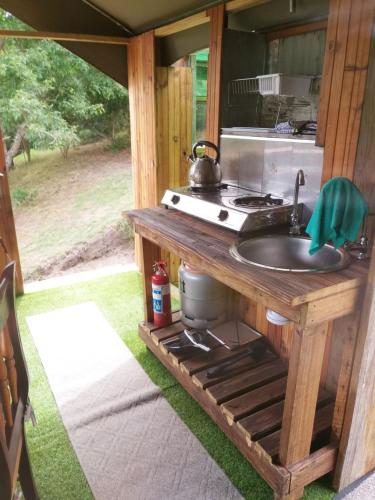an outdoor kitchen with a sink and a stove at Wilderness Glamping Tents in Wilderness