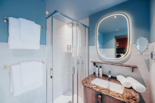 ein Bad mit einer Dusche, einem Waschbecken und einem Spiegel in der Unterkunft 1,75 Paris La Sève in Paris