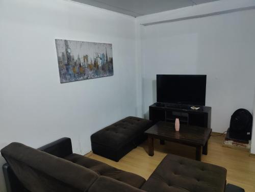 sala de estar con sofá y TV de pantalla plana en Acogedora Casa con Jardín, en Maldonado