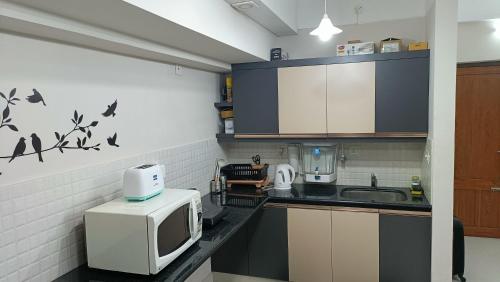 a small kitchen with a microwave and a sink at Safa Serviced Apartments in Cochin