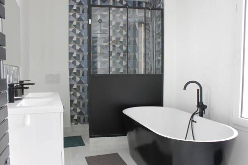 La salle de bains en noir et blanc est pourvue d'une baignoire et d'une douche. dans l'établissement Maison 85m2- 10min de Paris Centre - Ideal Olympics, à Houilles