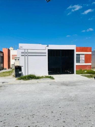 un bâtiment blanc avec une grande porte dans un parking dans l'établissement Departamento en Heroica Matamoros, à Matamoros