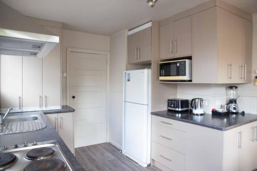 a kitchen with white cabinets and a white refrigerator at Kiwi bnb in Matamata