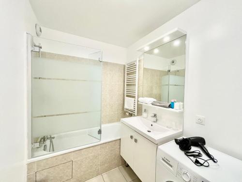 une salle de bain blanche avec un lavabo et une baignoire dans l'établissement Sunny apartment near Disneyland Paris – Liz Appart, à Serris