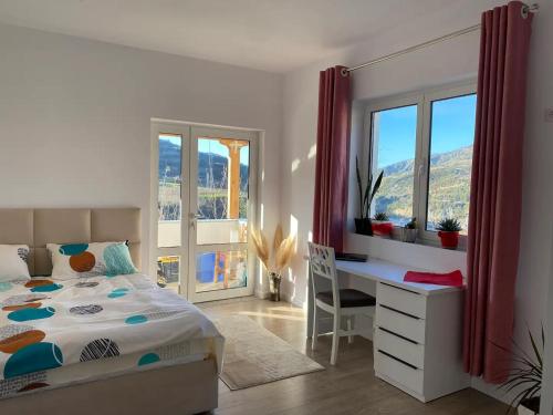 een slaapkamer met een bed, een bureau en ramen bij Großes und schönes Zimmer mit Balkon in Zhaban