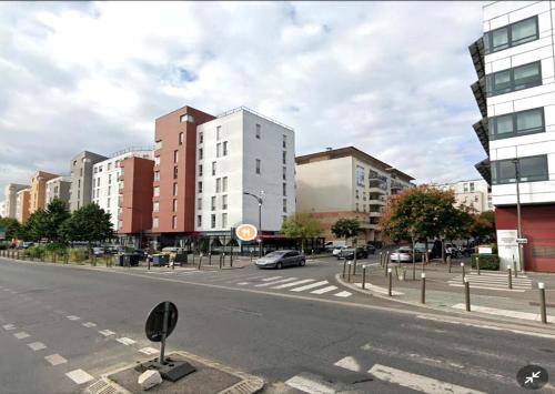 an empty city street with buildings and cars on the road at STUDIO proche du centre PARIS 15 min in Rosny-sous-Bois