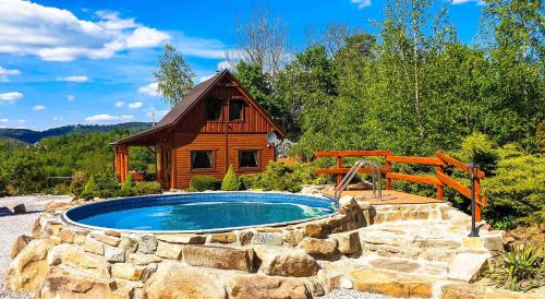 a swimming pool in front of a log cabin at Piaskowy Koń - Mountain Lodge & SPA- Karkonosze in Mniszków
