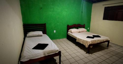 2 Betten in einem Zimmer mit grünen Wänden in der Unterkunft Flat Av Golfinhos in Pipa