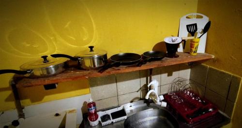 zwei Töpfe und Pfannen auf einem Regal über einer Küchenspüle in der Unterkunft Flat Av Golfinhos in Pipa
