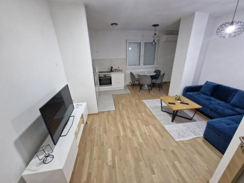 Apartman Centar Kozarska Dubica في Bosanska Dubica: غرفة معيشة مع أريكة زرقاء وطاولة
