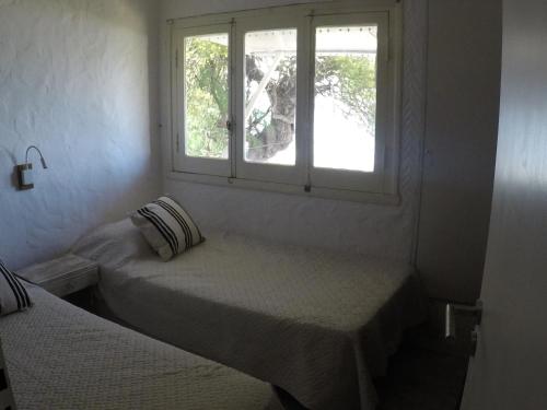 a white room with two beds and a window at San Miguel del monte 6 personas con pileta in San Miguel del Monte