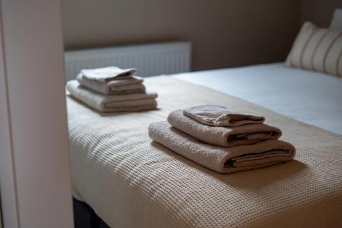two towels are stacked on the edge of a bed at Huisje Novea in Harderwijk
