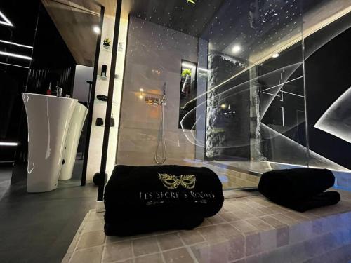 une salle de bain avec une douche et un sac noir sur le sol dans l'établissement Les Secrets Rooms/Love Room, à Rivesaltes