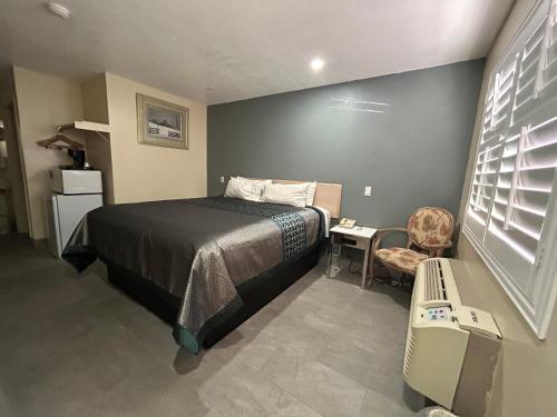 a small bedroom with a bed and a chair at California Inn Hotel and Suites Adelanto US 395 in Adelanto