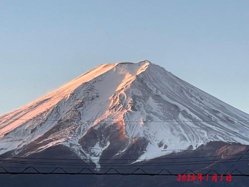 uma montanha coberta de neve com o topo de um edifício em Minshuku Nakano em Fujiyoshida