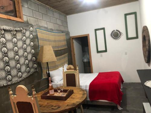 a bedroom with a bed and a table with a bottle of wine at Pousada Rosa Bonita in Praia do Rosa