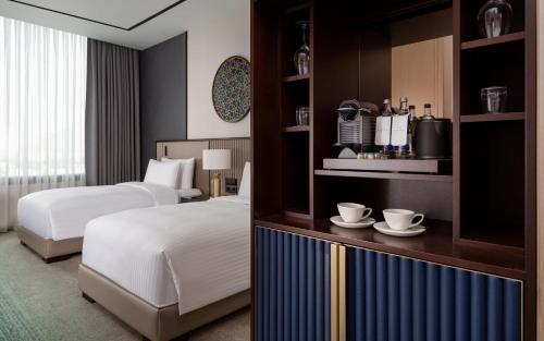 a hotel room with two beds and two cups on a shelf at InterContinental Tashkent by IHG in Tashkent