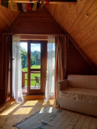 a living room with a couch and a large window at DZIUPLA - Berghaus in der Tatra mit Holzsauna in Brzegi