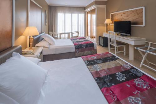 カンブリルスにあるMas Gallauのベッド2台とテレビが備わるホテルルームです。