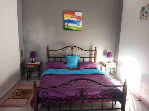 een slaapkamer met een paars bed en 2 nachtkastjes bij joli studio à louer in Meknès