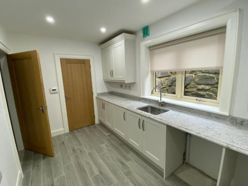 a kitchen with white cabinets and a sink at The Last Resort With Hot Tub And Car Service in Warrenpoint