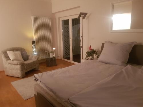 a bedroom with a bed and a chair and a window at Ferienwohnung Weserperle in Nordenham