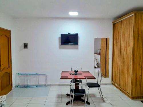 a room with a table and chairs and a tv on a wall at Chalé Recanto Luz Da Montanha in Águas de Lindóia