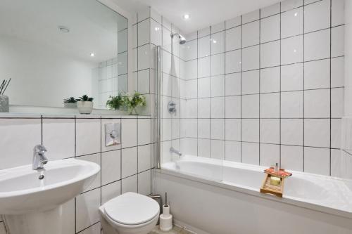 a white bathroom with a toilet and a sink at Spacious 4 Beds Apt - Perfect for Families, Contractors & FREE Parking in Leeds