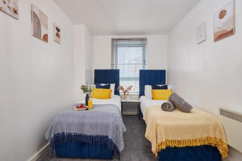 2 Betten in einem Zimmer mit blauen und gelben Kissen in der Unterkunft Spacious 4 Beds Apt - Perfect for Families, Contractors & FREE Parking in Leeds