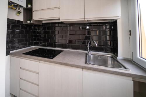 una cocina con fregadero de acero inoxidable y azulejos negros en AG apartment en Cormano