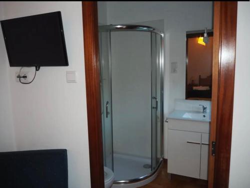 TV y baño con ducha y lavabo. en Monte Carlo - Alojamento Local, en Pedras Salgadas
