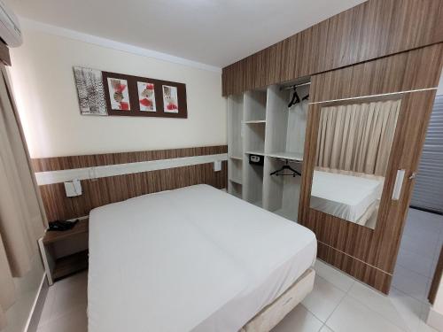 um quarto com uma cama branca e uma parede de madeira em Lacqua diRoma RM Hospedagem em Caldas Novas