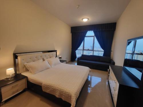 a bedroom with a bed and a couch and a television at Beachfront Holiday Homes in Ajman 