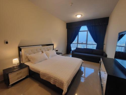 a bedroom with a bed and a couch and a television at Beachfront Holiday Homes in Ajman 