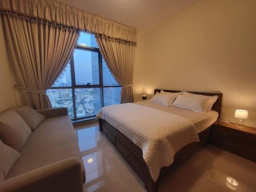 a bedroom with a bed and a couch and a window at Beachfront Holiday Homes in Ajman 