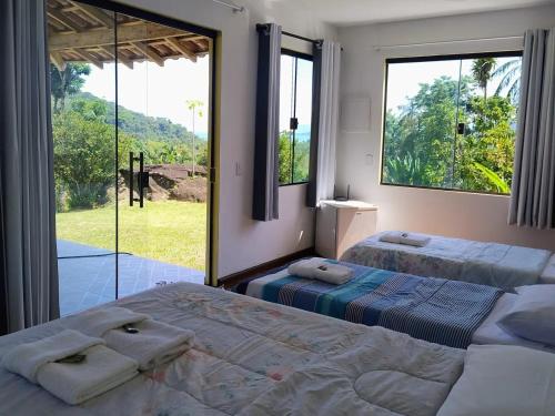a bedroom with two beds and a large window at Pousada Porto Taquari in Paraty