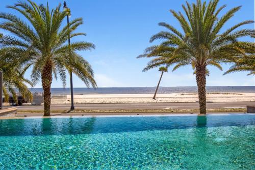 a swimming pool with palm trees and a beach at Holiday Inn Express - Gulfport Beach by IHG in Gulfport