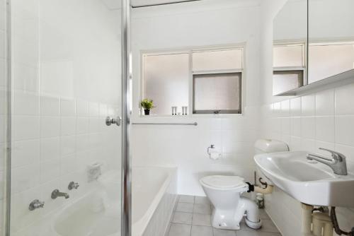 een witte badkamer met een toilet en een wastafel bij Belle Escapes - Broadway by The Beach in Glenelg
