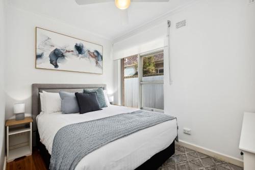 een slaapkamer met een groot bed en een raam bij Belle Escapes - Broadway by The Beach in Glenelg