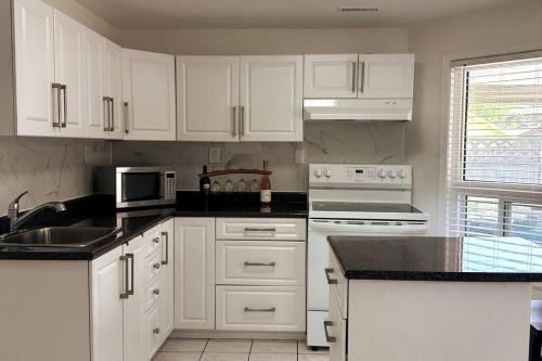 a kitchen with white cabinets and white appliances at Walkout basement apartment in Mississauga