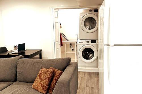 a living room with a couch and a washer and dryer at Walkout basement apartment in Mississauga