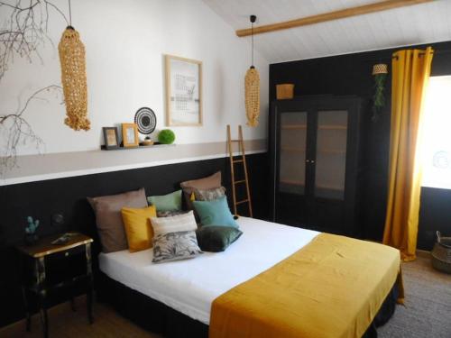 a bedroom with a large bed with colorful pillows at Maison 3 étoiles , proche plages, Cotinière, & St Pierre in La Cotinière