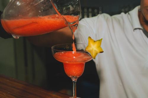 a man is pouring a red drink into a glass at Hotel El Cocobolo Food&Rest Room 1 B&B WiFi AC Pkg Free Swimmingpool in Ahogados