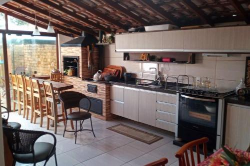 uma cozinha com uma mesa, cadeiras e um fogão em Casa Sobrado com piscina Santa Felicidade 6 pessoa em Curitiba