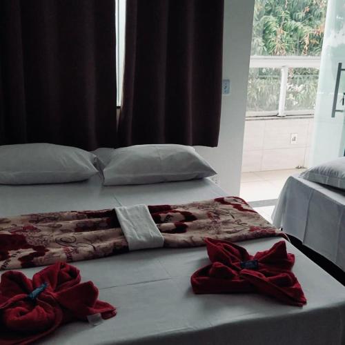 a bed with red roses on it with a window at Pousada Portico de Buzios in Armacao dos Buzios