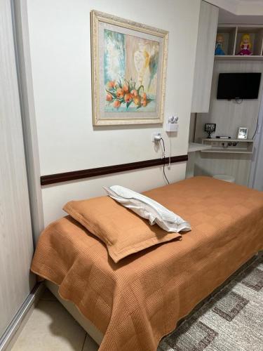 a bed in a room with a painting on the wall at Quarto privativo em casa domiciliar in Campo Grande