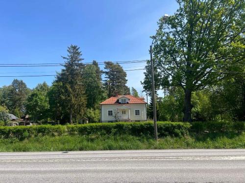 uma pequena casa branca na berma de uma estrada em Lugnet em Skebobruk